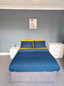 a bedroom with a blue bed with two white cabinets at Spacious large room 001 in Nottingham