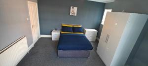 a bedroom with a bed with blue walls and yellow pillows at Spacious large room 001 in Nottingham