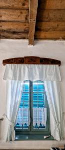 a window with white curtains and blue dishes in it at Dézsavár Vendégház in Majs