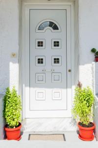 eine weiße Tür mit zwei Topfpflanzen davor in der Unterkunft Villa of byron in Kastraki