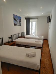 リスボンにあるHouse Rooms in Bairro Altoのベッド3台と窓が備わる客室です。