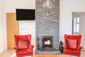 two red chairs in front of a fireplace at An Teachain in Ballynabola