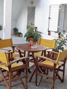 einen Holztisch mit gelben Stühlen sowie einem Tisch und Stühlen in der Unterkunft Villa of byron in Kastraki
