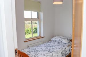 um pequeno quarto com uma cama e uma janela em An Teachain em Ballynabola