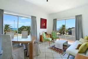 a living room with a couch and a table and chairs at Brighton Court in Campsbay on the beach. in Cape Town