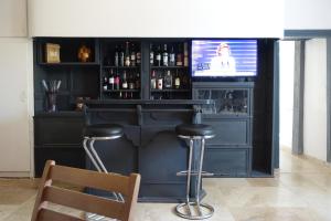 eine Bar mit Hockern und einen TV in einem Zimmer in der Unterkunft La maison Cayré in Mirandol-Bourgnounac