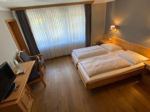 Schlafzimmer mit einem Bett, einem Schreibtisch und einem TV in der Unterkunft Flux-Biohotel Werratal in Hannoversch Münden