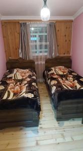 twee bedden in een kamer met een raam bij Guesthouse Solomon in Chvibiani
