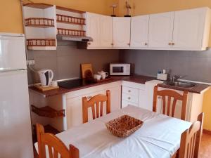 a kitchen with white cabinets and a table with a basket on it at Casa Palmés in Valles de Ortega