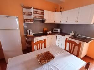 uma cozinha com armários brancos e uma mesa com cadeiras em Casa Palmés em Valles de Ortega