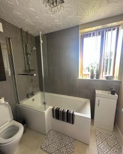 a bathroom with a bath tub and a toilet at Entire 2 bedroom house. in Rowley Regis