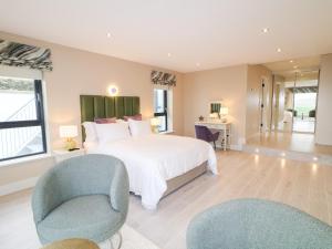 a bedroom with a large white bed and two chairs at The Beachhouse in Cashel Hill