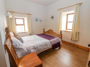 a bedroom with a bed and two windows at Clogher Cottage in Doonbeg