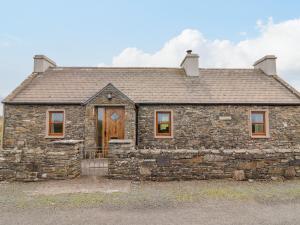 une ancienne maison en pierre avec une porte en bois dans l'établissement Clogher Cottage, à Doonbeg