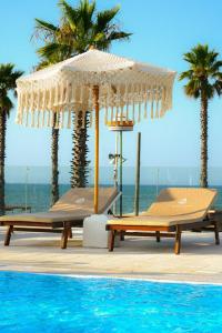 einen Pool mit zwei Stühlen und einem Sonnenschirm am Meer in der Unterkunft Valerio Resort beach club in Margherita di Savoia