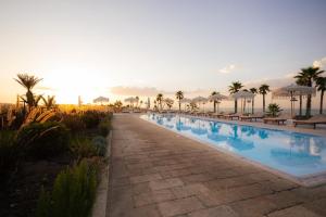ein großer Pool mit Sonnenschirmen und Palmen in der Unterkunft Valerio Resort beach club in Margherita di Savoia