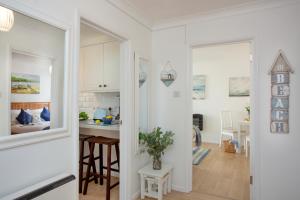 a kitchen and living room with white cabinets and a table at The Sail Loft in Sidmouth