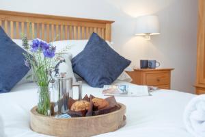a tray with cookies and a vase of flowers on a bed at The Sail Loft in Sidmouth
