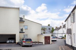 a row of white buildings with cars parked in a parking lot at The Sail Loft in Sidmouth