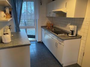奥斯科瑟羅的住宿－Seeblick Wohnung 112 mit Ostseeblick，厨房配有白色橱柜、水槽和窗户。