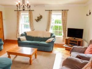 a living room with a blue couch and a tv at Reeks Cottage in Killorglin