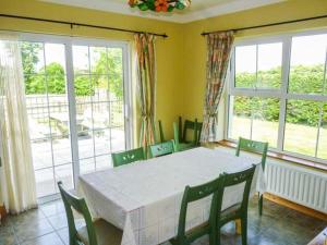a dining room with a table and chairs and windows at Reeks Cottage in Killorglin
