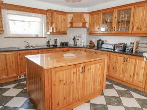 a kitchen with wooden cabinets and a large island at Bluebell House and Gardens in Rossbrin