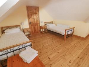 a room with two beds and a wooden floor at Bluebell House and Gardens in Rossbrin