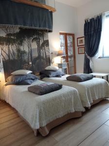 two beds in a bedroom with blue curtains at Le Château de Roquebère in Condom