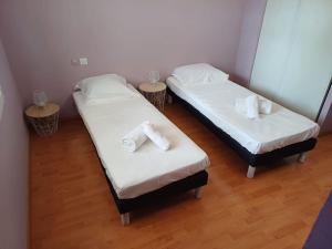 two beds in a room with white sheets and towels at L'Inattendue in Castelnau-le-Lez