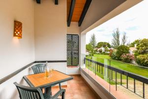 a balcony with a wooden table and chairs and a view at Pedras D'el Rei in Tavira