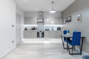 a kitchen with white cabinets and a table and chairs at LiveStay - Modern & Stylish Apartments in Oxfordshire in Didcot