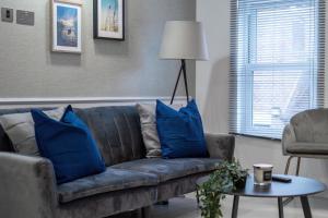 a living room with a couch with blue pillows at LiveStay - Modern & Stylish Apartments in Oxfordshire in Didcot