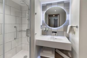 bagno bianco con lavandino e specchio di Hampton By Hilton Dublin City Centre a Dublino