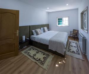 a bedroom with a bed and a door and two rugs at Retiro do Prior in Chaves