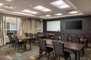 a conference room with tables and chairs and a screen at Residence Inn by Marriott Denver Central Park in Denver