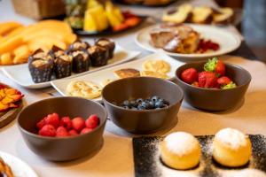 a table topped with bowls of fruit and pastries at Hotel Alt Spaur in Spormaggiore