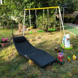 a playground with a swing and toys in the grass at Apartments "Sun-sea" in Rab