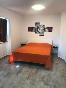 a bedroom with a bed with orange sheets and pictures on the wall at Luciae Domus in Roccascalegna