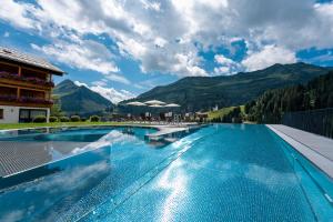 a large swimming pool with mountains in the background at Hotel Alpenblume in Damuls