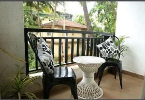 balcón con 2 sillas, mesa y ventana en Bella vista, en Candolim