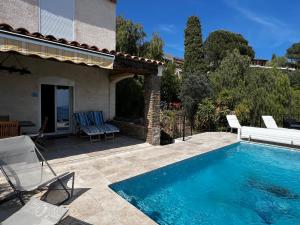 a swimming pool with chairs and a house at La Villa Pavilou in Le Lavandou