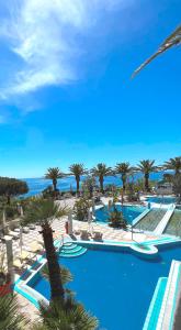 vistas a una piscina del complejo con palmeras y al océano en Borgo Romantica - Resort & Spa en Ischia