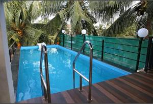 una piscina azul con barandillas de metal junto a una terraza de madera en Bella vista, en Candolim