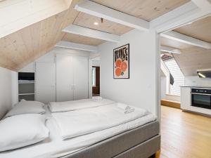 スタヴァンゲルにあるCharming Rooftop Apartment In Heart Of Stavangerの白い壁と木製の天井が特徴の客室で、大型ベッド1台を利用できます。