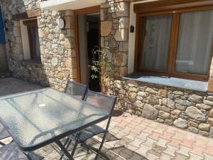 une table et des chaises devant un bâtiment en pierre dans l'établissement Cathy, aux Angles