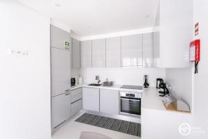 uma cozinha branca com armários e electrodomésticos brancos em Home Azores - Casas da Ladeira em Ponta Delgada