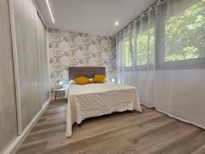 a bedroom with a bed with yellow pillows and a window at 1B105 Bonito apartamento en zona exclusiva in Gijón