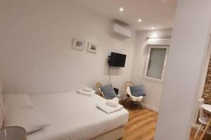 Habitación blanca con 1 cama y 2 sillas en Cozy studio in Madrid Rio with backyard-EM-ISA-A2, en Madrid