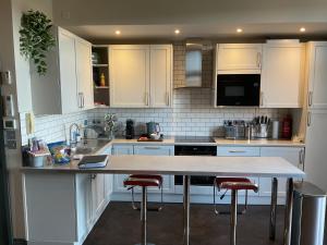 伦敦Queens View的厨房配有白色橱柜和带凳子的台面